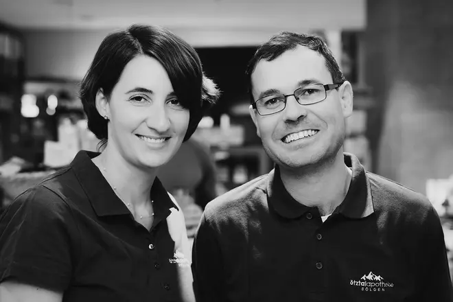Schwarz-Weiß Foto der Apotheken Inhaber. Die Frau und der Mann lachen beide in die Kamera.